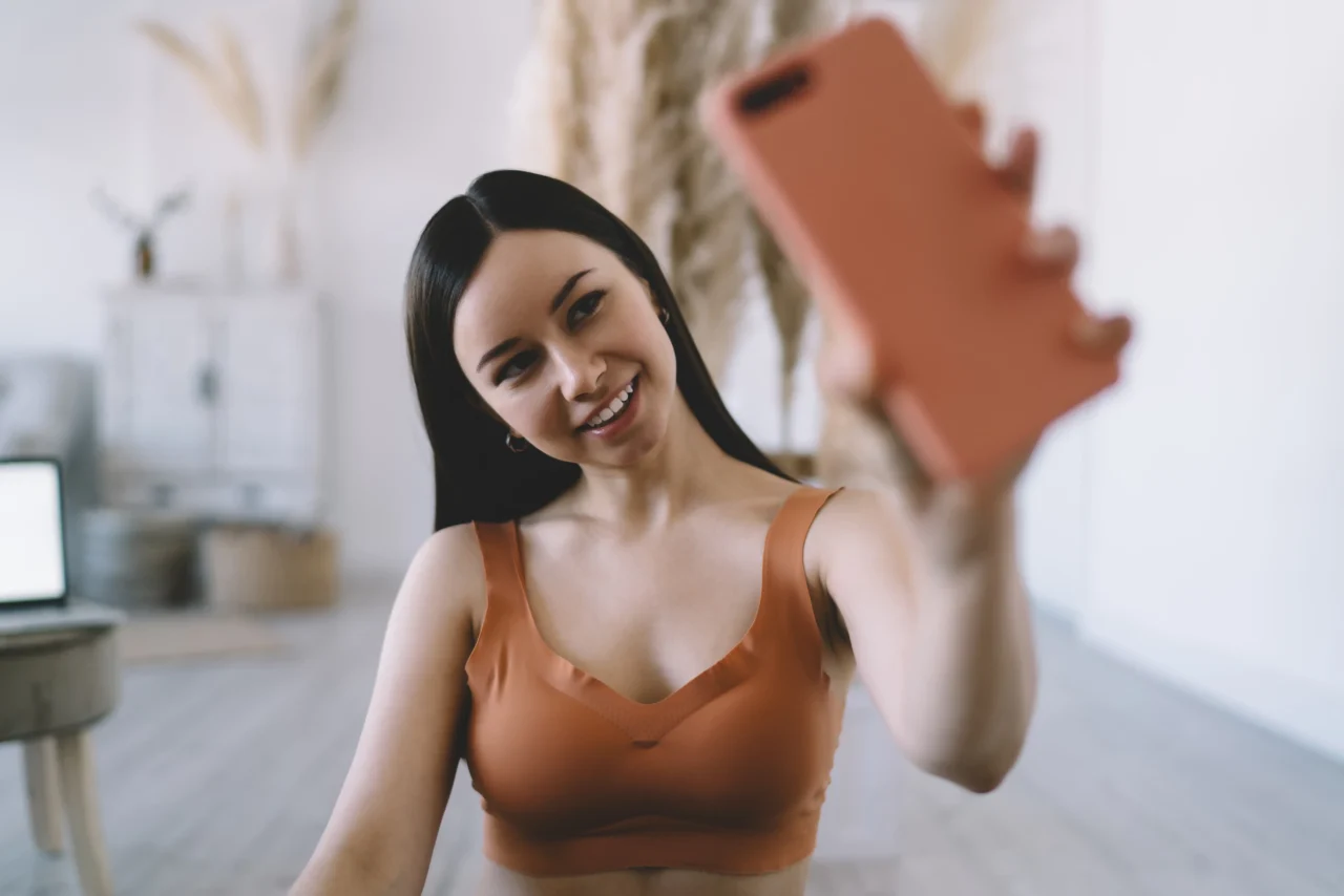 Joven sonriente haciéndose un selfie con su móvil, ejemplo de creadora de contenido digital en OnlyFans