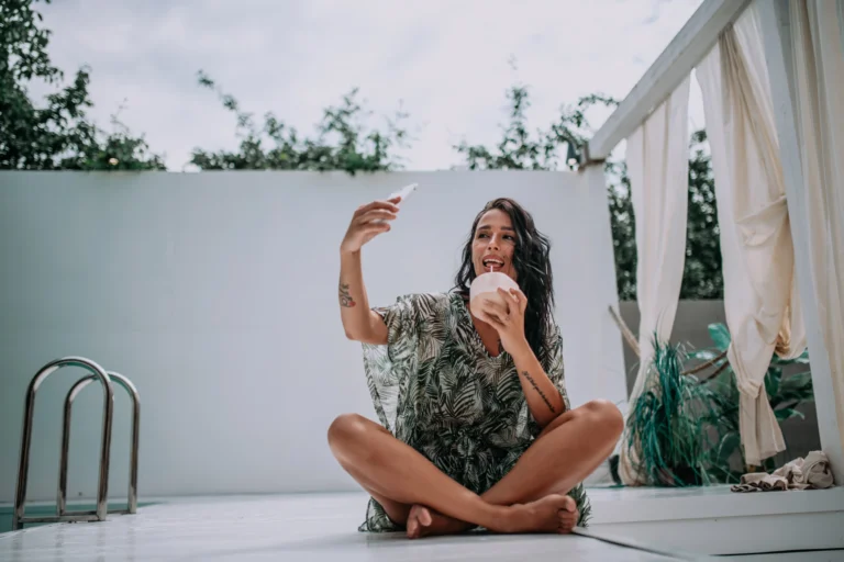 "Mujer joven grabando un vídeo selfie en una terraza con piscina, mostrando su estilo de vida natural y cercano para conectar con su audiencia.