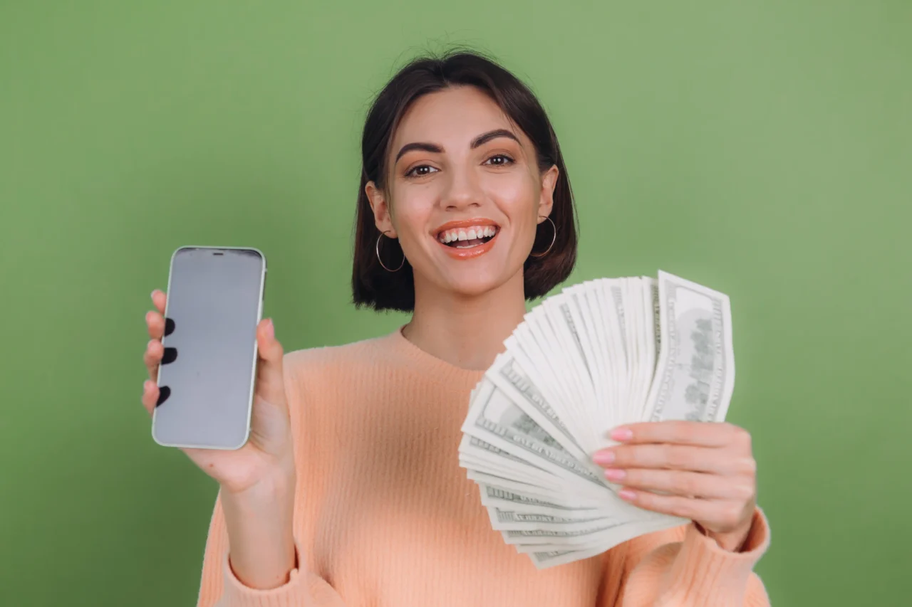 Joven mostrando un fajo de billetes y un teléfono móvil, representando ingresos obtenidos en plataformas digitales como OnlyFans.